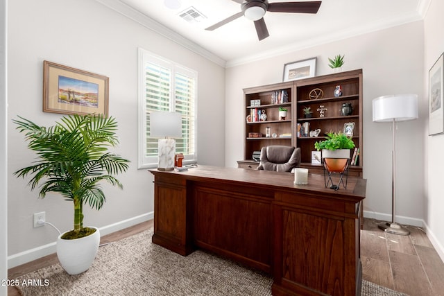 office space with visible vents, light wood-style flooring, a ceiling fan, crown molding, and baseboards