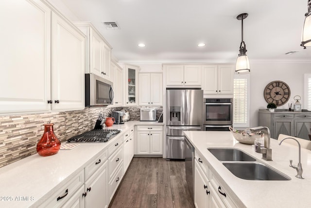 kitchen featuring visible vents, light countertops, ornamental molding, appliances with stainless steel finishes, and a sink