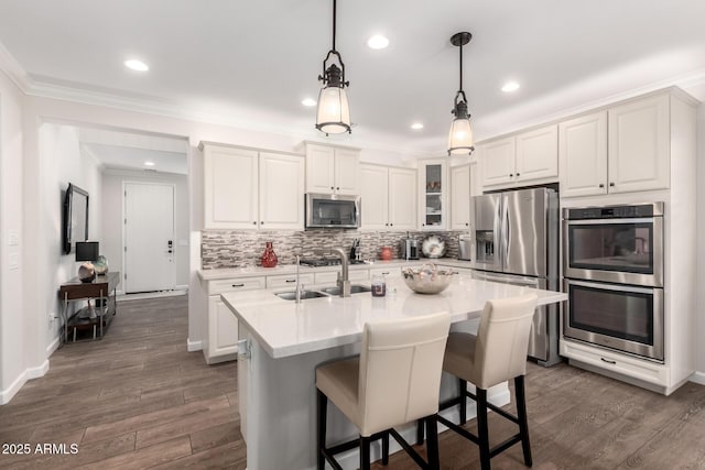 kitchen featuring tasteful backsplash, crown molding, light countertops, appliances with stainless steel finishes, and a sink