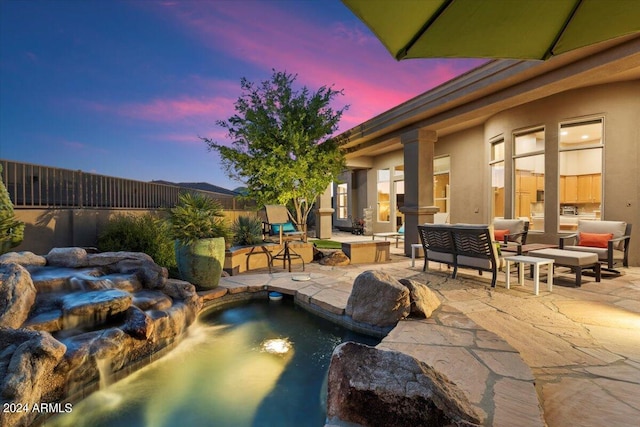 pool at dusk featuring a patio and pool water feature