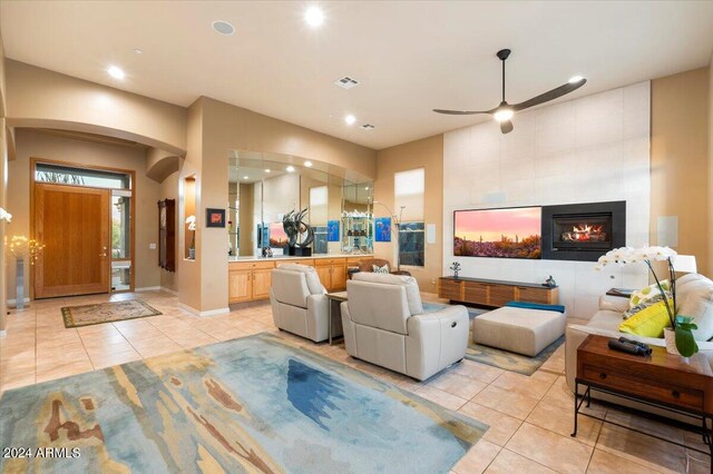 tiled living room with ceiling fan and a fireplace