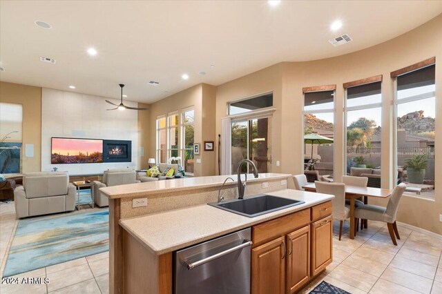 kitchen featuring stainless steel dishwasher, a kitchen island with sink, sink, and light tile patterned flooring