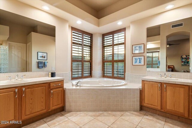 bathroom featuring tile patterned flooring, ceiling fan, tiled bath, and vanity