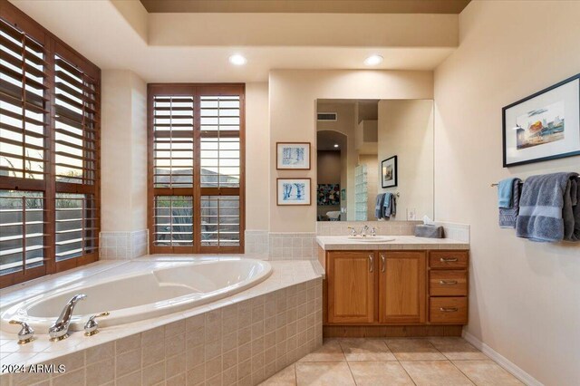 bathroom with tile patterned floors, tiled bath, and vanity