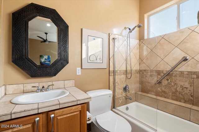 full bathroom featuring tiled shower / bath combo, vanity, and toilet