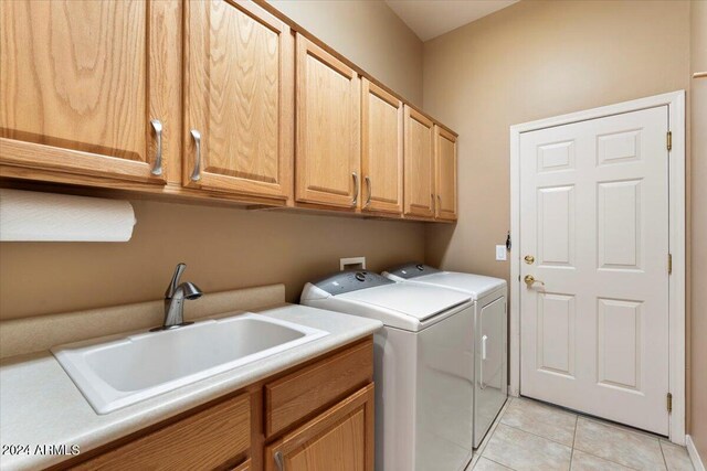 washroom with separate washer and dryer, light tile patterned flooring, sink, and cabinets