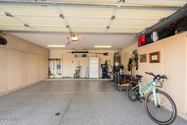 garage featuring a garage door opener, water heater, and white fridge