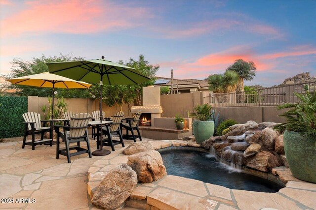 patio terrace at dusk with pool water feature and a fenced in pool