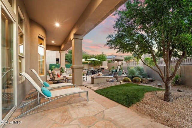 patio terrace at dusk with an outdoor living space with a fire pit