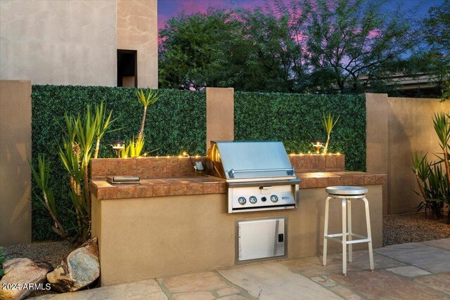 patio terrace at dusk featuring area for grilling and a grill