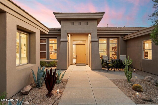 exterior entry at dusk featuring a patio