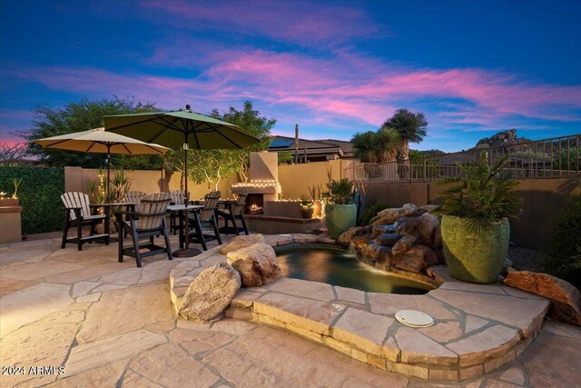 patio terrace at dusk with an outdoor stone fireplace