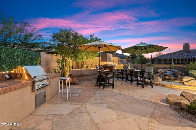 patio terrace at dusk featuring area for grilling