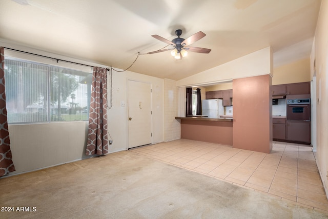 unfurnished living room with ceiling fan, light tile patterned floors, and vaulted ceiling