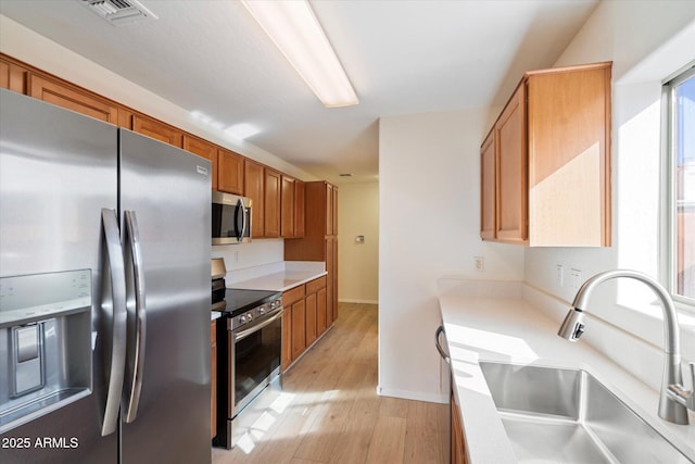 kitchen with stainless steel appliances, light hardwood / wood-style floors, and sink