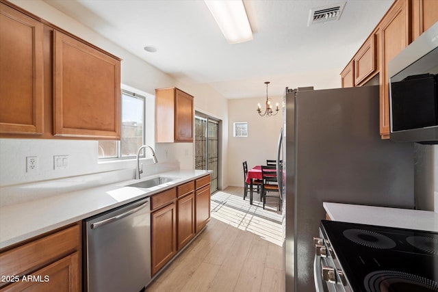 kitchen featuring sink, decorative light fixtures, light wood-type flooring, a notable chandelier, and stainless steel appliances