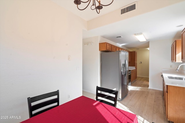 dining space featuring sink, light hardwood / wood-style flooring, and a notable chandelier