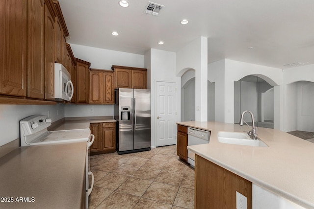 2425 W Red Range Way, Phoenix, AZ 85085 - kitchen with white appliances, light countertops, arched walkways, recessed lighting, and brown cabinetry