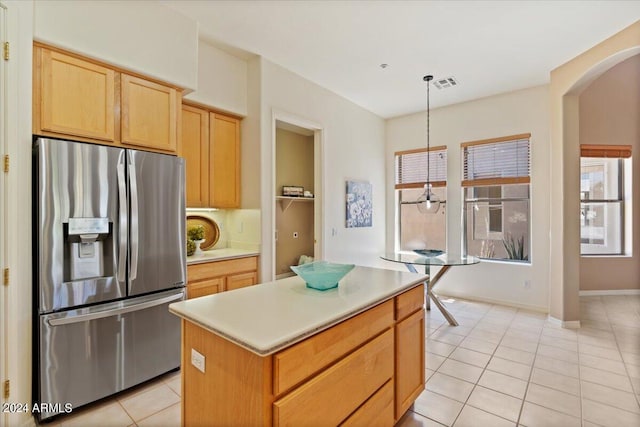 kitchen featuring stainless steel refrigerator with ice dispenser, plenty of natural light, a kitchen island, and hanging light fixtures