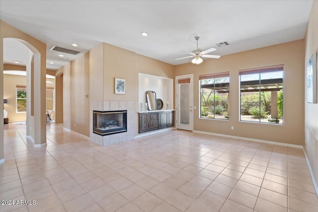 unfurnished living room featuring a tile fireplace, light tile patterned flooring, and ceiling fan