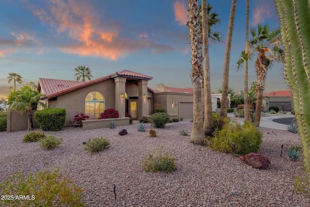 mediterranean / spanish-style home featuring a tiled roof, driveway, stucco siding, and an attached garage