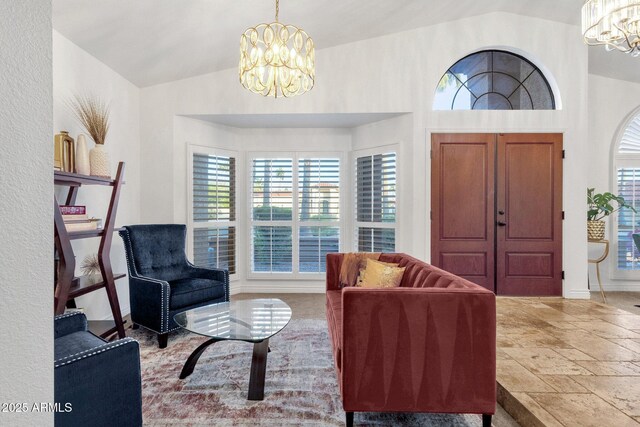 living room featuring stone tile flooring, a notable chandelier, and lofted ceiling