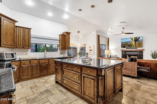 kitchen with a center island, a toaster, a sink, ceiling fan, and stone tile flooring