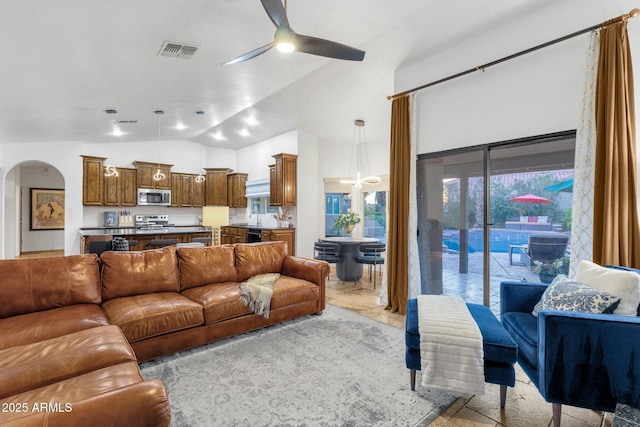 living room featuring a ceiling fan, arched walkways, high vaulted ceiling, and visible vents