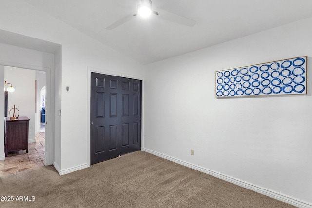 unfurnished bedroom with vaulted ceiling, carpet, baseboards, a ceiling fan, and a closet