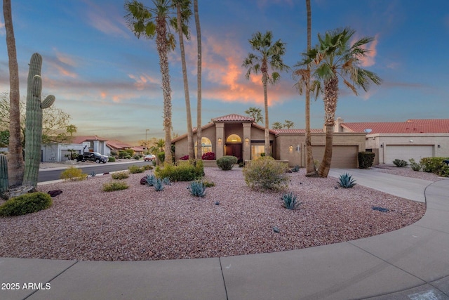 view of front of home featuring driveway, stucco siding, an attached garage, and a tiled roof