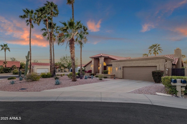 mediterranean / spanish house with driveway, stucco siding, a tile roof, and an attached garage