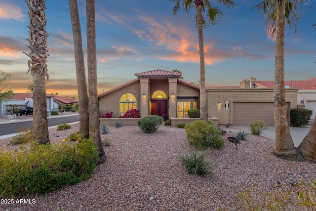 mediterranean / spanish-style house with driveway, stucco siding, an attached garage, and a tiled roof