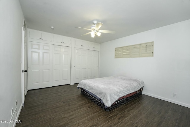 bedroom featuring ceiling fan, dark hardwood / wood-style floors, and two closets