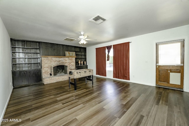 living room featuring built in shelves, ceiling fan, a fireplace, and wood-type flooring