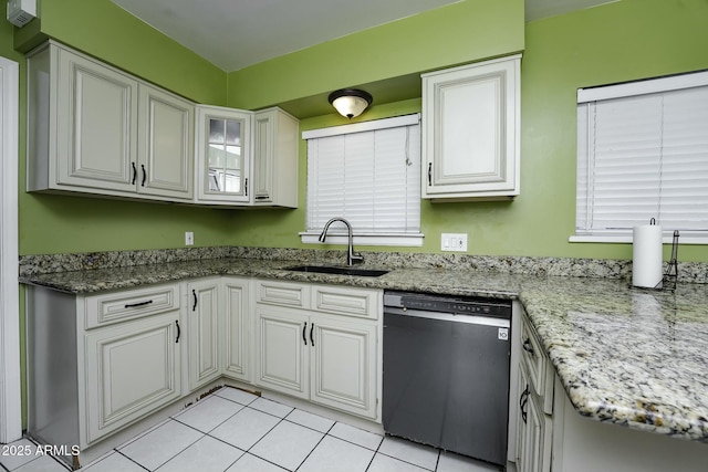 kitchen with dishwasher, sink, light tile patterned flooring, light stone counters, and white cabinetry