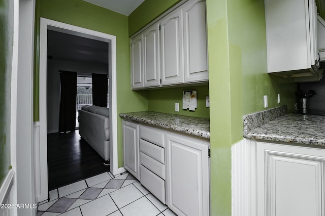 kitchen featuring white cabinets, light stone countertops, and light tile patterned floors