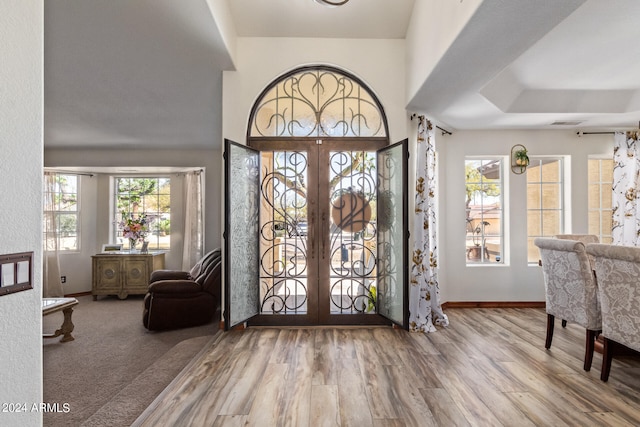 foyer featuring french doors, a tray ceiling, and wood-type flooring