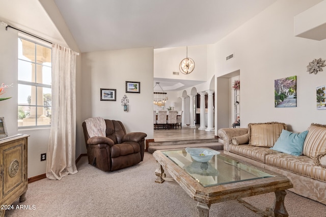 carpeted living room featuring high vaulted ceiling, decorative columns, and a notable chandelier