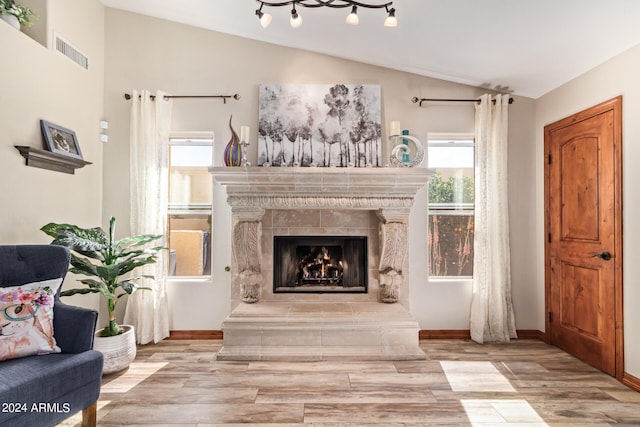 interior space featuring a fireplace, rail lighting, vaulted ceiling, and light wood-type flooring