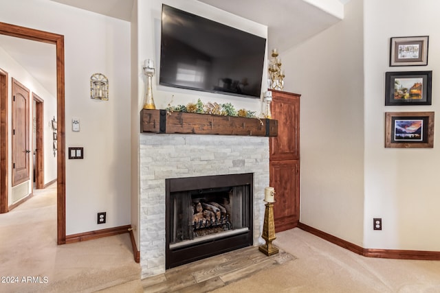 carpeted living room with a stone fireplace