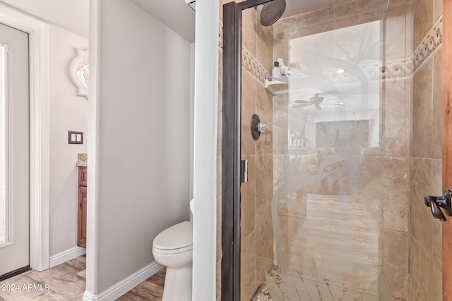 bathroom featuring hardwood / wood-style floors, a shower with door, ceiling fan, and toilet