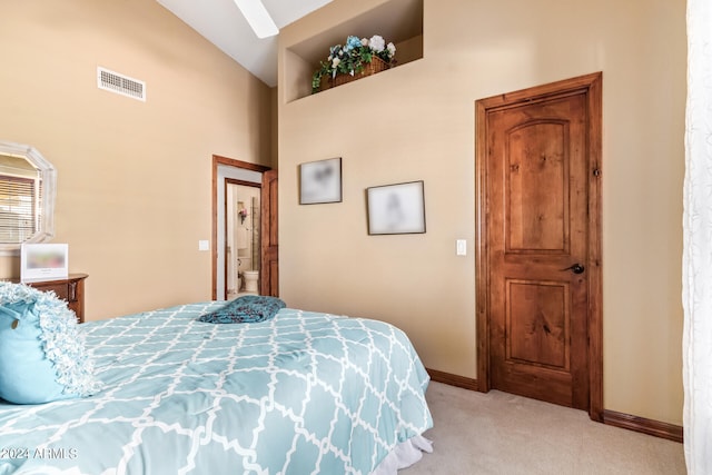 carpeted bedroom featuring high vaulted ceiling and ensuite bath