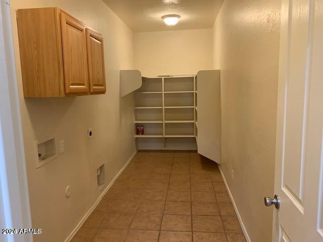 interior space featuring gas dryer hookup, hookup for an electric dryer, washer hookup, light tile patterned floors, and cabinets