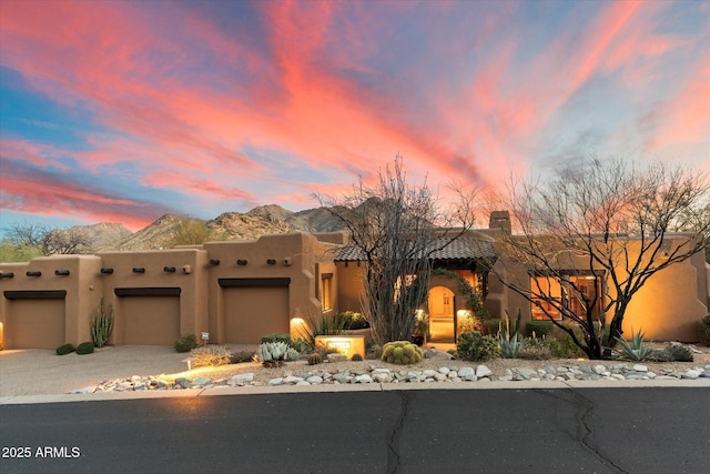 adobe home featuring a mountain view, an attached garage, and driveway