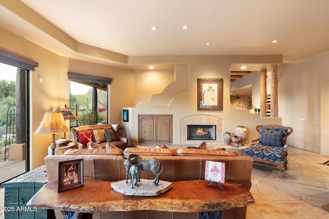 living room with recessed lighting and a warm lit fireplace