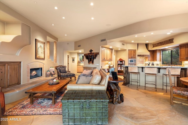 living area with recessed lighting, visible vents, and a lit fireplace