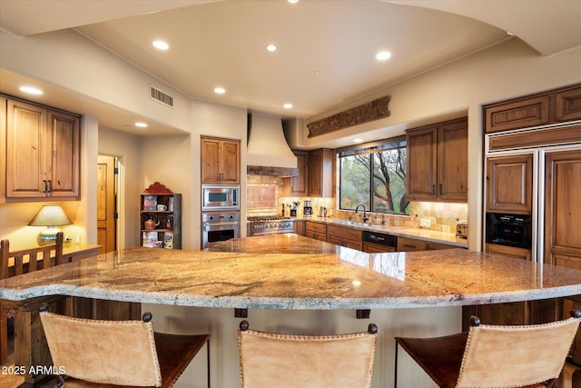 kitchen with tasteful backsplash, visible vents, built in appliances, light stone counters, and custom exhaust hood