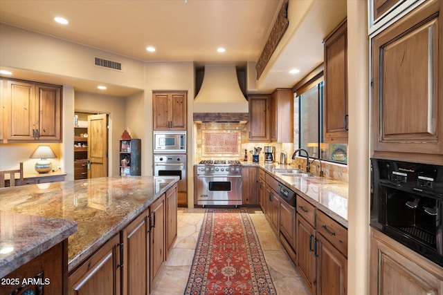 kitchen featuring visible vents, premium range hood, stone counters, a sink, and stainless steel appliances