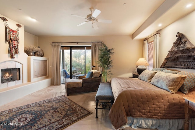 bedroom with a warm lit fireplace, ceiling fan, and access to outside