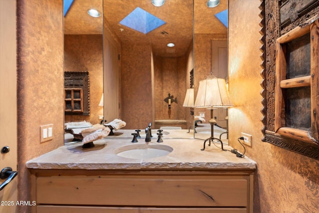 bathroom featuring recessed lighting, a skylight, and vanity